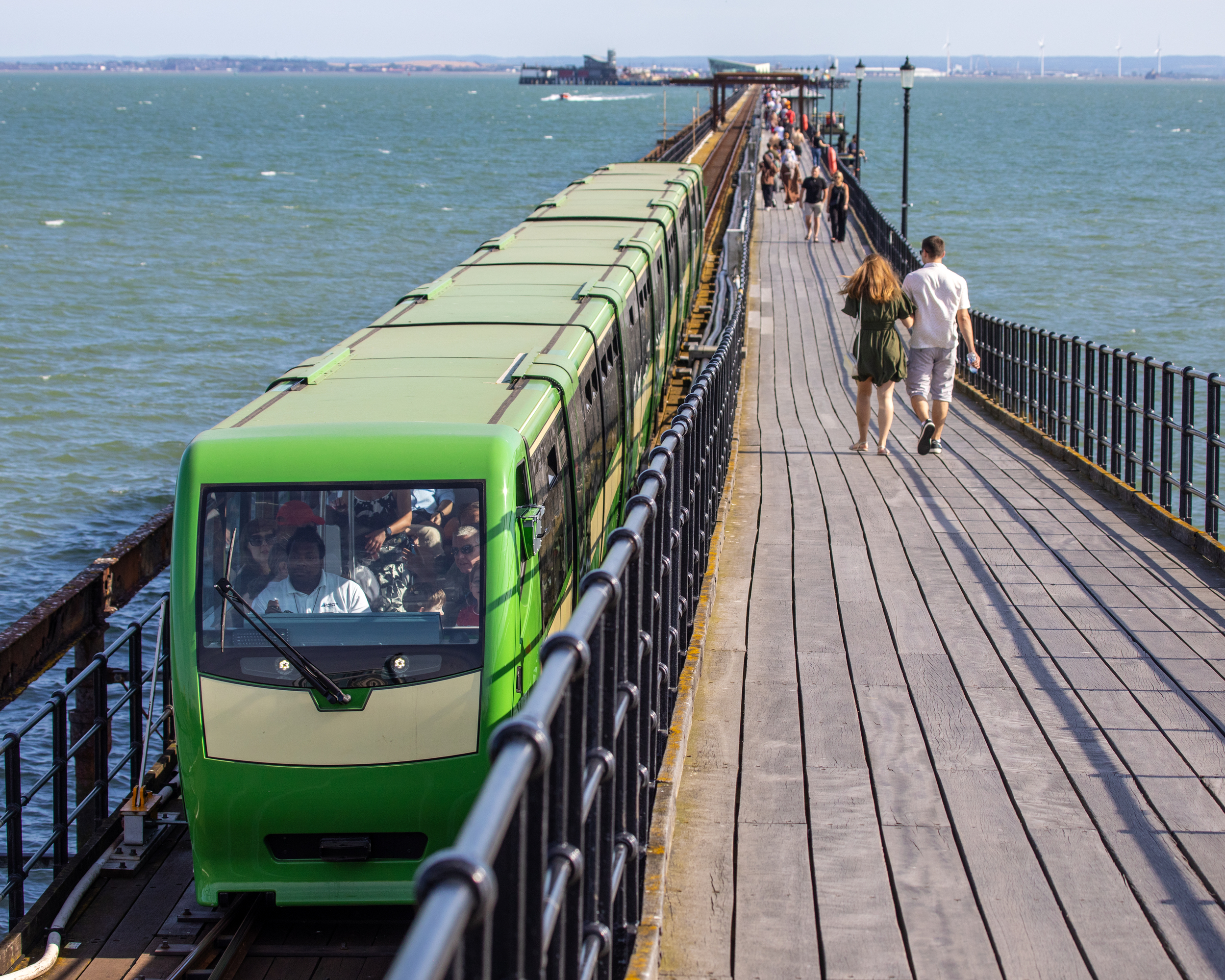 Southend Pier Railway train alongside visitors walking along Southend Pier over the Thames Estuary.